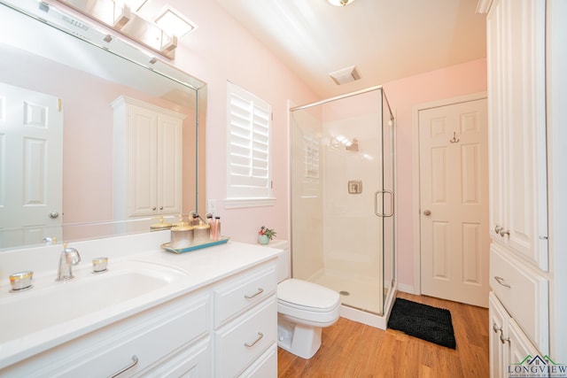 bathroom with a stall shower, toilet, vanity, and wood finished floors