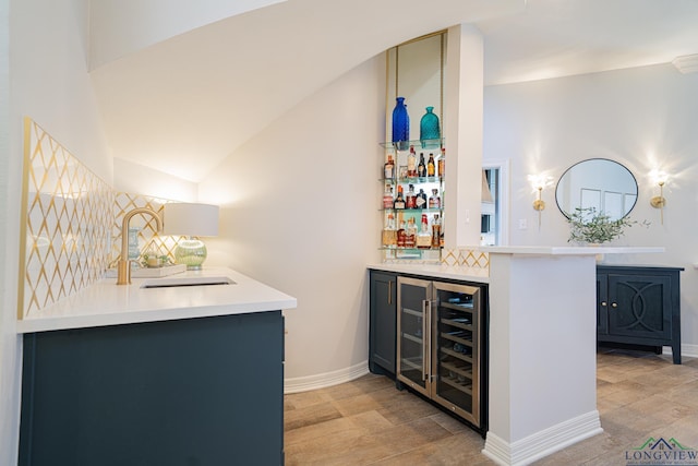 bar featuring baseboards, a sink, vaulted ceiling, wine cooler, and a dry bar