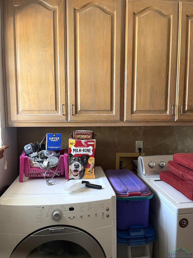 clothes washing area with cabinets and independent washer and dryer