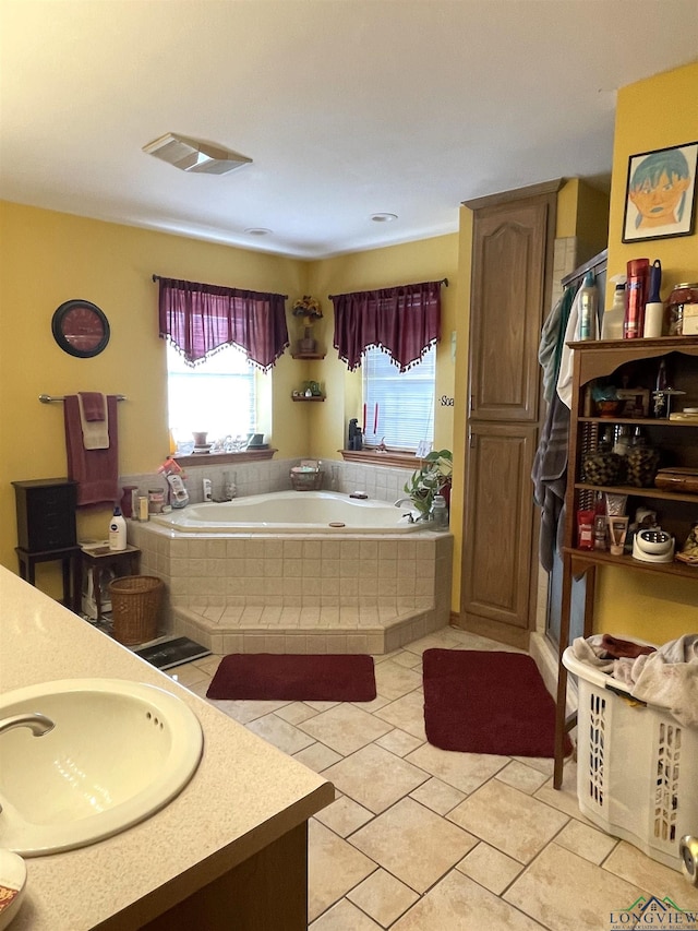 bathroom featuring tile patterned flooring, vanity, and tiled tub