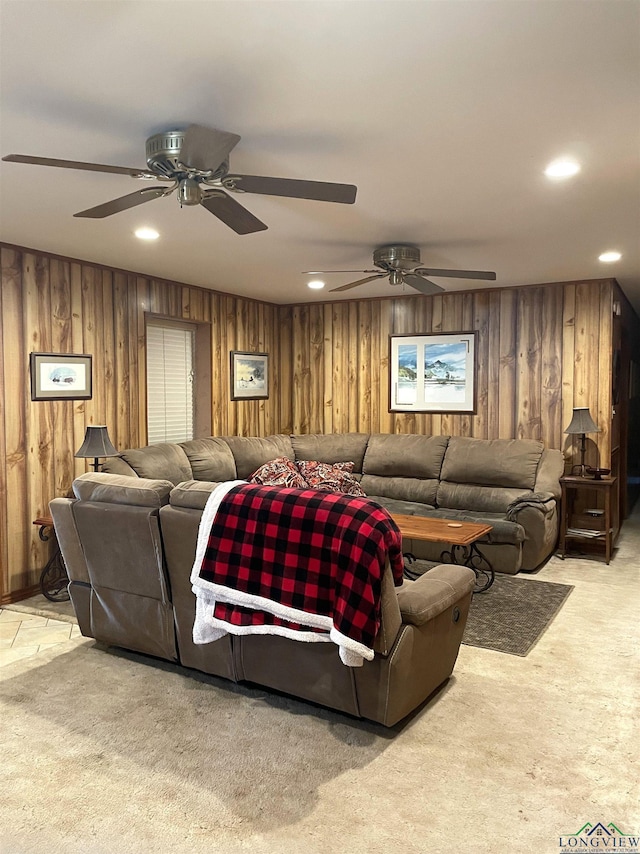 living room with ceiling fan, wooden walls, and light colored carpet