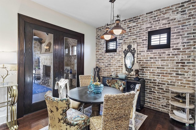 dining area featuring dark wood-type flooring and brick wall