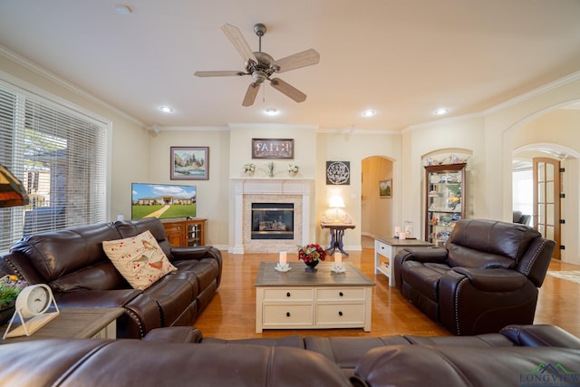 living area featuring arched walkways, crown molding, and wood finished floors