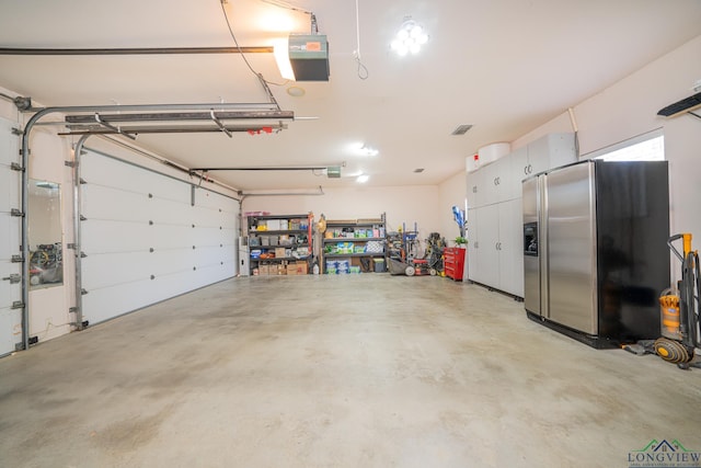 garage featuring stainless steel refrigerator with ice dispenser and a garage door opener