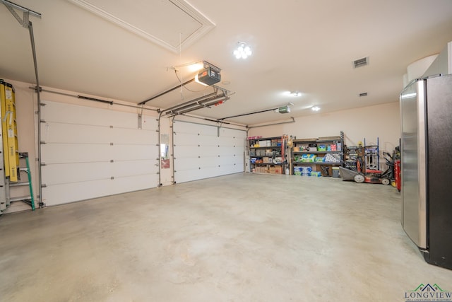 garage with a garage door opener, freestanding refrigerator, and visible vents