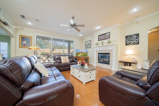 living area with arched walkways, a healthy amount of sunlight, light wood-style flooring, and a tiled fireplace