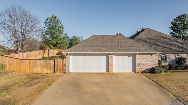 view of front of property featuring brick siding, roof with shingles, a front yard, fence, and a garage