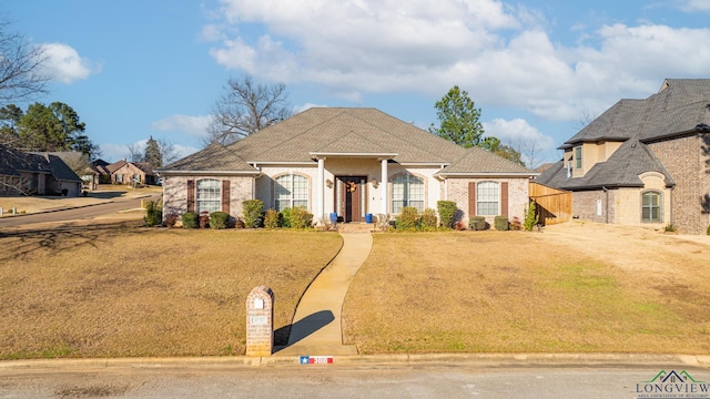 french country style house featuring brick siding and a front yard