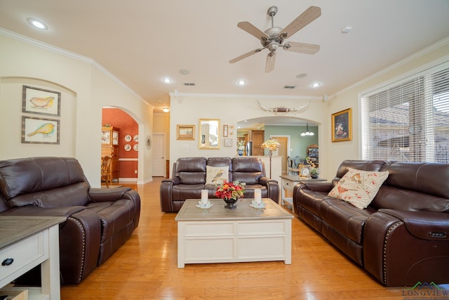 living room with arched walkways, light wood finished floors, a ceiling fan, and crown molding