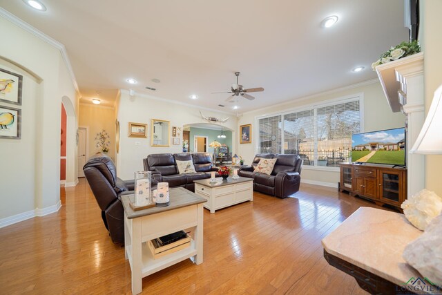 living room featuring light wood-style floors, arched walkways, and crown molding