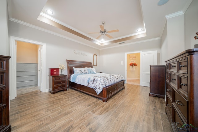 bedroom with light wood-type flooring, a raised ceiling, visible vents, and crown molding