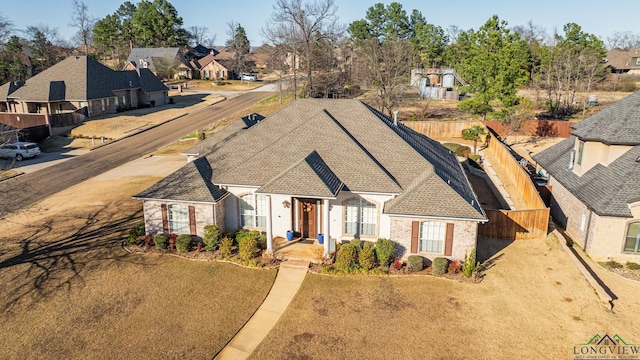 view of front of house featuring a shingled roof, a residential view, and fence