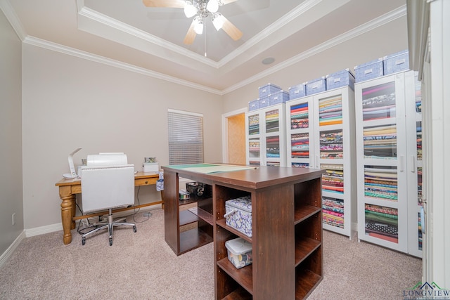 carpeted office with a ceiling fan, baseboards, a raised ceiling, and crown molding