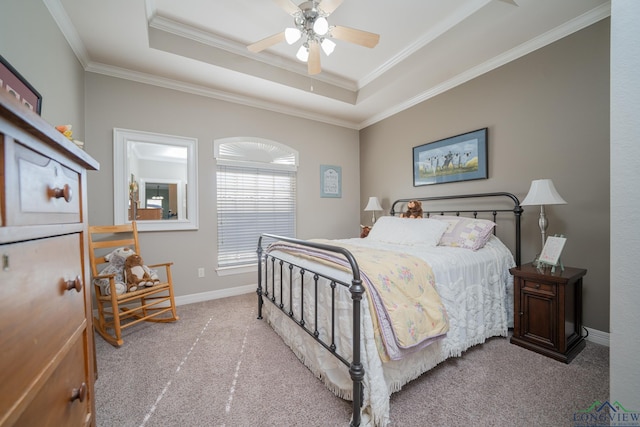 carpeted bedroom with a ceiling fan, a tray ceiling, crown molding, and baseboards