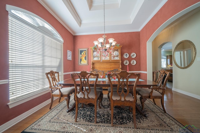 dining area with arched walkways, baseboards, hardwood / wood-style floors, and a tray ceiling