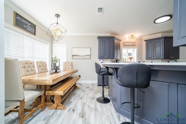 dining space featuring light hardwood / wood-style flooring, crown molding, and a notable chandelier