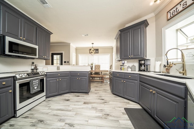 kitchen featuring sink, pendant lighting, gray cabinets, appliances with stainless steel finishes, and ornamental molding