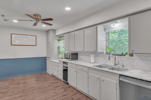 kitchen featuring a ceiling fan, tasteful backsplash, a sink, dishwasher, and visible vents