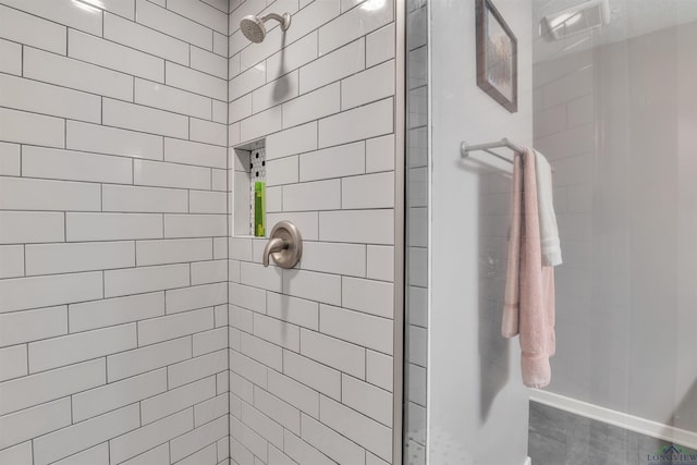 full bathroom featuring a tile shower and baseboards