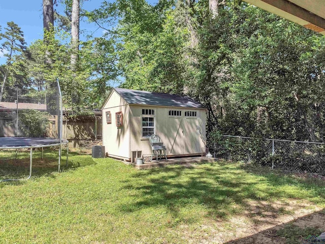 view of shed featuring a fenced backyard, central air condition unit, and a trampoline