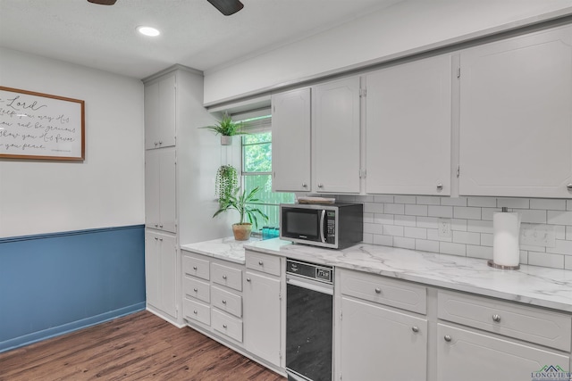 kitchen with stainless steel microwave, decorative backsplash, light stone countertops, and dark wood-type flooring