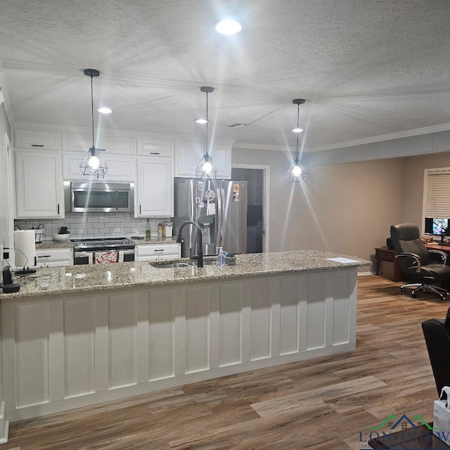 kitchen with pendant lighting, sink, light stone counters, stainless steel appliances, and a textured ceiling