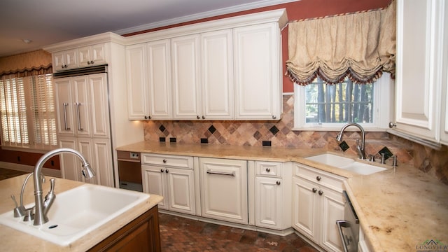 kitchen with backsplash, crown molding, white cabinetry, and sink