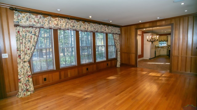 spare room featuring hardwood / wood-style flooring, ornamental molding, and an inviting chandelier