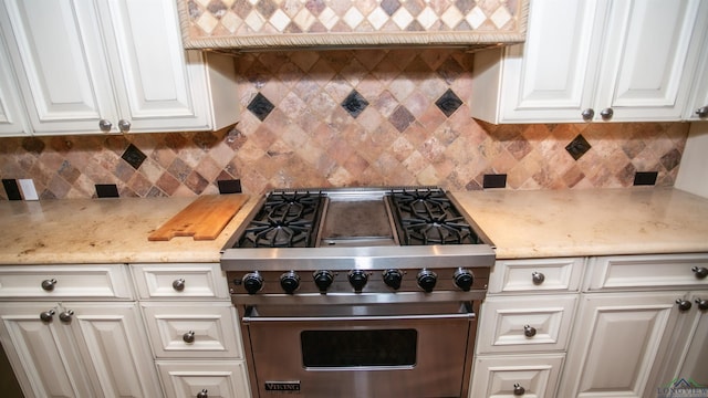 kitchen with decorative backsplash, white cabinets, light stone countertops, and premium range