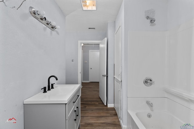 bathroom with hardwood / wood-style floors, vanity, a textured ceiling, and shower / bathtub combination