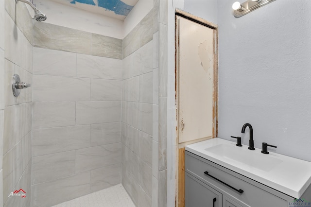 bathroom with a tile shower and vanity