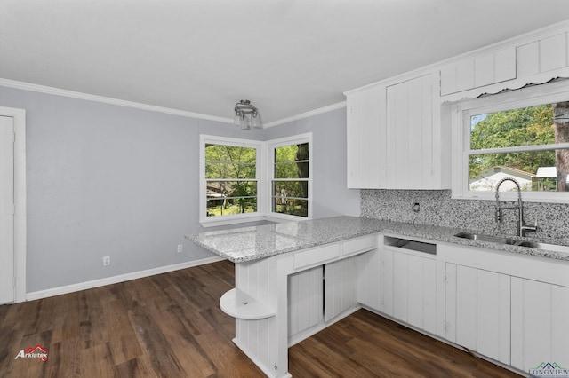 kitchen with kitchen peninsula, white cabinetry, sink, and light stone counters