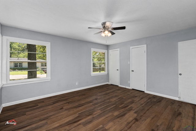 unfurnished bedroom featuring multiple windows, dark hardwood / wood-style flooring, two closets, and ceiling fan