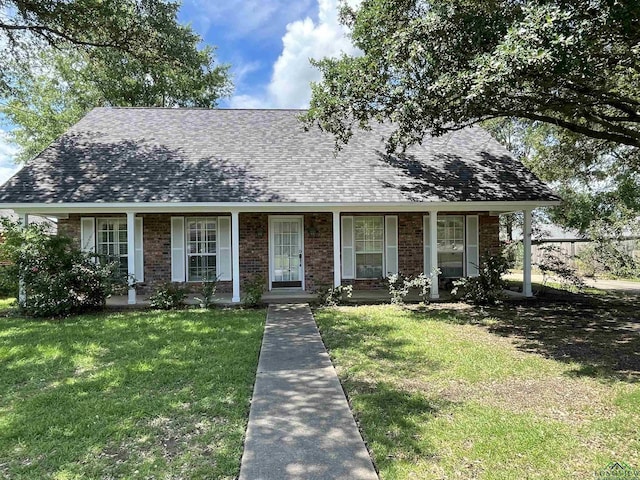1404 Stonebriar Dr, Carthage, TX 75633 - view of front of home with roof with shingles, a front yard, brick siding, and covered porch