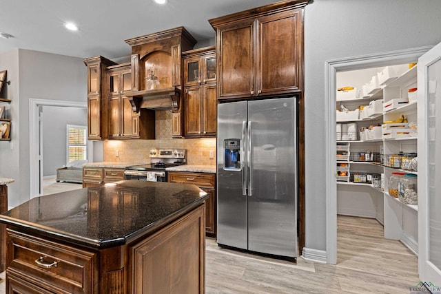 kitchen with a kitchen island, appliances with stainless steel finishes, and dark stone counters