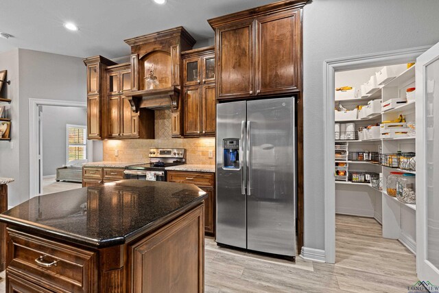 kitchen with a kitchen island, appliances with stainless steel finishes, and dark stone counters