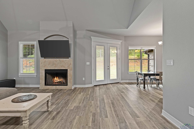 living room featuring french doors, hardwood / wood-style flooring, vaulted ceiling, and a tiled fireplace