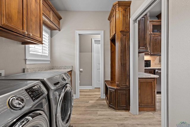 laundry room with cabinets, washing machine and dryer, and light hardwood / wood-style floors