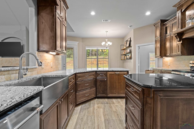 kitchen with decorative backsplash, light stone counters, stainless steel appliances, sink, and an inviting chandelier