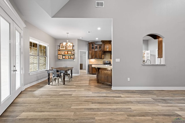 kitchen with tasteful backsplash, hanging light fixtures, light hardwood / wood-style floors, and a notable chandelier