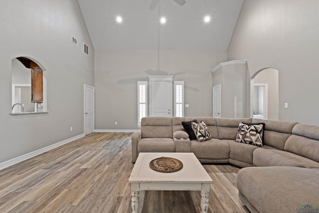 living room featuring light hardwood / wood-style flooring, high vaulted ceiling, and ceiling fan