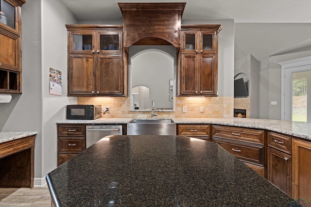 kitchen featuring stainless steel dishwasher, dark stone countertops, sink, and tasteful backsplash