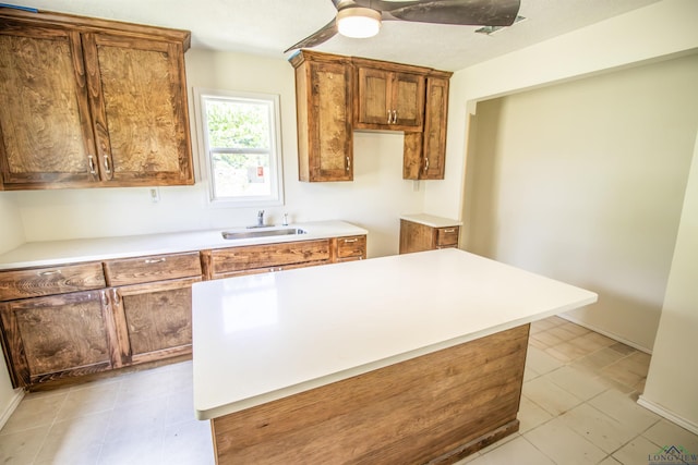 180 Martha St, Waskom, TX 75692 - kitchen with a sink, brown cabinets, a center island, light countertops, and light tile patterned flooring