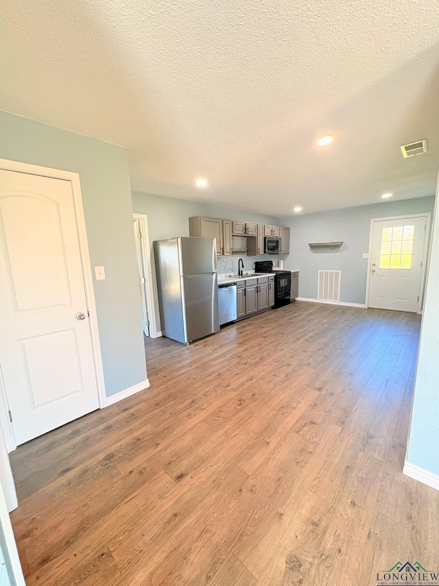 kitchen featuring stainless steel appliances, light wood finished floors, light countertops, and visible vents