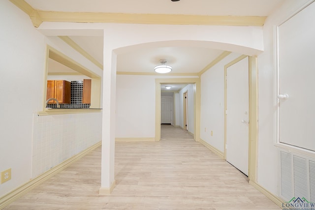 hallway featuring ornamental molding and light hardwood / wood-style floors