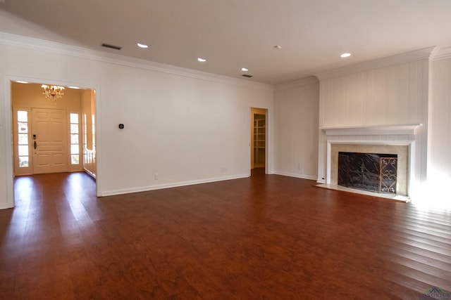 unfurnished living room with dark wood-type flooring, a chandelier, a high end fireplace, and ornamental molding