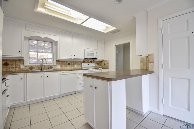 kitchen with sink, backsplash, white cabinetry, light tile patterned floors, and white appliances