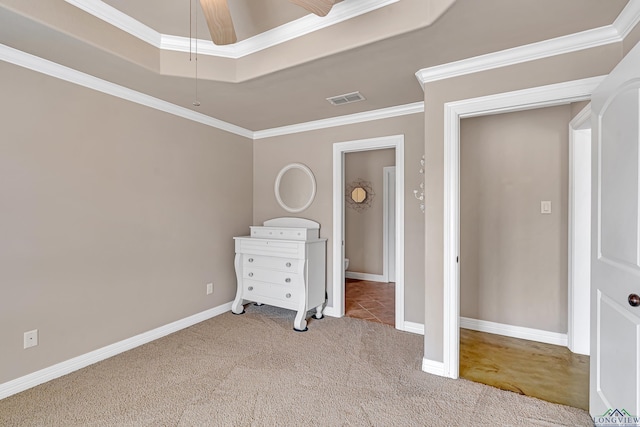 unfurnished bedroom with baseboards, visible vents, a tray ceiling, crown molding, and carpet flooring