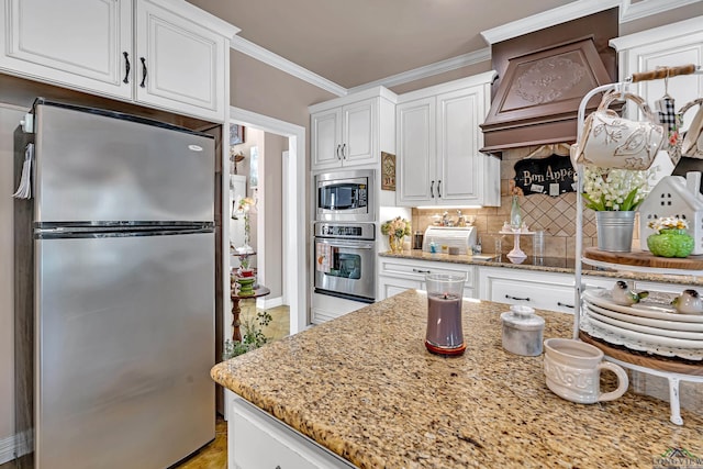 kitchen featuring appliances with stainless steel finishes, white cabinetry, crown molding, and tasteful backsplash