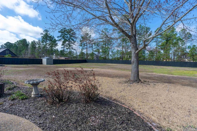 view of yard featuring a shed, fence, and an outbuilding